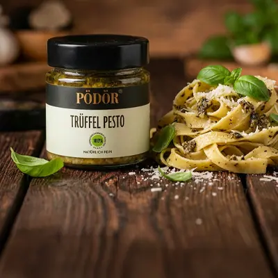Pödör Trüffel Pesto im Glas neben einem Pastagericht.